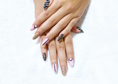 Woman's hands with patterns on each nail, black and white chevron, pink checvron, gold sparkles, black polka dots, black and gold sparkle
